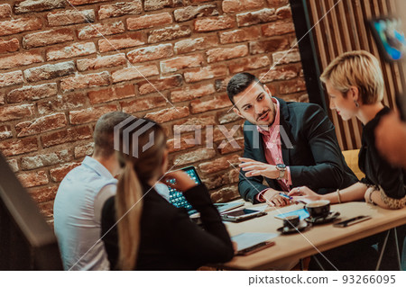Happy businesspeople smiling cheerfully during a meeting in a coffee shop. Group of successful business professionals working as a team in a multicultural workplace. Happy businesspeople smiling cheerfully during a meeting in a coffee shop. Group of successful business professionals working as a team in a multicultural workplace. 93266095