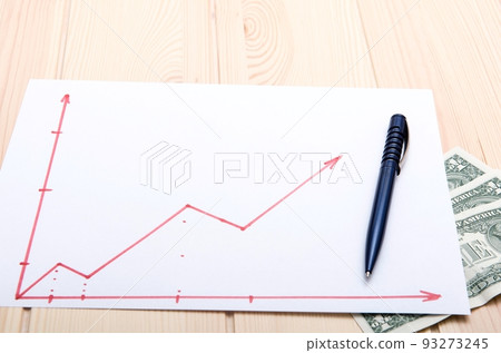 A sheet of paper depicting a drawing of a graph of rising stock prices depicting a stock market for securities with dollars under the paper A sheet of paper depicting a drawing of a graph of rising stock prices depicting a stock market for securities with dollars under the paper 93273245