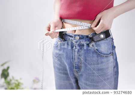 Young woman measuring waist Young woman measuring waist 93274680