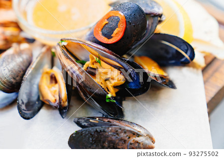 seafood. mussel cooked on the grill with sauce and vegetables.  93275502