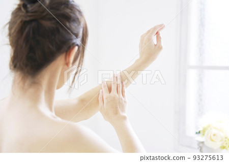 Back view of a woman taking care of her arms in the living room 93275613