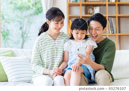 A young family looking at a smartphone in the living room A young family looking at a smartphone in the living room 93276107