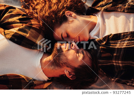 View from above, young couple in love lying facing each other and morning sunlight shines on them 93277245