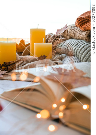 Book on first plan Thanksgiving and Hello Fall, celebrating autumn holidays at cozy home on the windowsill Hygge atmosphere Autumn leaves, spices and candle on cozy knitted sweater in warm yellow Book on first plan Thanksgiving and Hello Fall, celebrating autumn holidays at cozy home on the windowsill Hygge atmosphere Autumn leaves, spices and candle on cozy knitted sweater in warm yellow 93277898