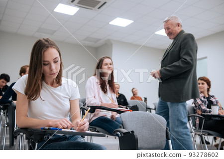 An elderly teacher at a technical university conducts a lecture for first-year students in the college auditorium An elderly teacher at a technical university conducts a lecture for first-year students in the college auditorium 93278602