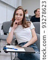 Portrait of a young pretty girl student during college classes, she is sitting in the audience among other student 93278623