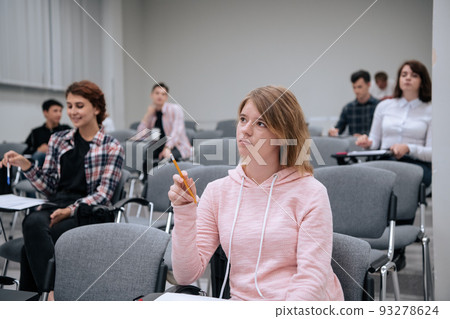 College students listen attentively to the professors lecture, sitting on chairs in a large audience College students listen attentively to the professors lecture, sitting on chairs in a large audience 93278624