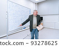 A gray-haired famous professor in a jacket and jeans shows his way of solving the theorem at a training seminar for teachers 93278625