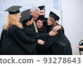 A wise elderly university professor rejoices together with his students in robes and hats at the end of their studies 93278643