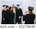 At the university, during the presentation of graduation diplomas, students in beautiful robes and hats are photographed with their dean of the faculty 93278646