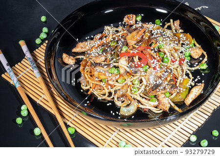 Udon noodles with meat, mushrooms and vegetables. Sprinkled with sesame seeds. Asian food, roast on black background, 93279729