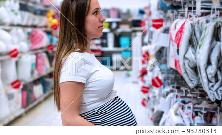 Baby care powder pregnancy woman shopping. Young pregnant woman buying on baby bath shampoo bottle on supermarket background. Baby care products market choice. 93280313