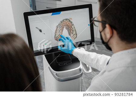 Male doctor show results of digital intraoral scan of patient teeth in 3D on display. 93281784