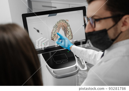 Male doctor show results of digital intraoral scan of patient teeth in 3D on display. 93281786