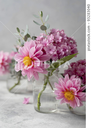 Still life pink flowers scene. Pink hydrangea flowers and dahlias in glass vase on neutral background soft, selective focus. Still life pink flowers scene. Pink hydrangea flowers and dahlias in glass vase on neutral background soft, selective focus. 93283040
