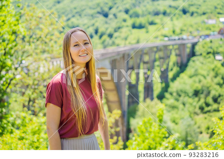 Montenegro. Woman tourist in background of Dzhurdzhevich Bridge Over The River Tara. Travel around Montenegro concept. Sights of Montenegro Portrait of a disgruntled girl sitting at a cafe table 93283216