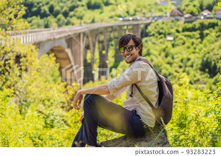 Montenegro. Man tourist in background of Dzhurdzhevich Bridge Over The River Tara. Travel around Montenegro concept. Sights of Montenegro Portrait of a disgruntled girl sitting at a cafe table 93283223