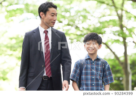 Male elementary school student and father walking while talking with a smile Male elementary school student and father walking while talking with a smile 93284399