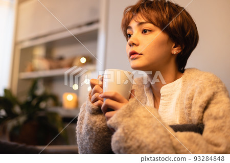 Woman drinking a hot drink in the living room at night 93284848