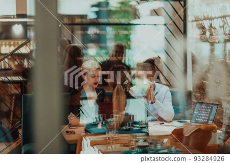 Happy businesspeople smiling cheerfully during a meeting in a coffee shop. Group of successful business professionals working as a team in a multicultural workplace. Happy businesspeople smiling cheerfully during a meeting in a coffee shop. Group of successful business professionals working as a team in a multicultural workplace. 93284926