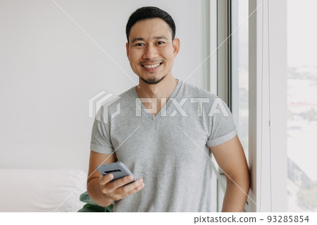 Young happy smiling asian man using smartphone feels relax and comfortable. Young happy smiling asian man using smartphone feels relax and comfortable. 93285854