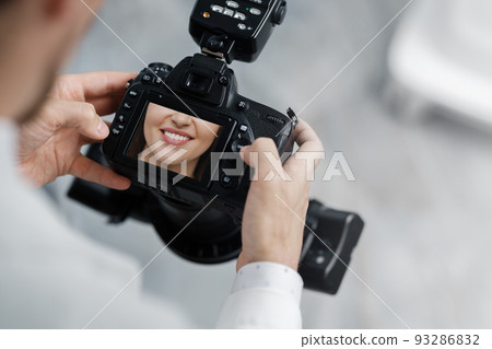 Dentist holding photo camera with picture of healthy smile on a screen. Dentist holding photo camera with picture of healthy smile on a screen. 93286832