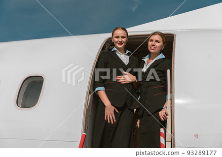 Two Women flight attendant standing on airplane stairs at airport and looking camera before flight 93289177