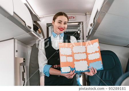 Smiling Female flight attendant holding instruction booklet before flight Smiling Female flight attendant holding instruction booklet before flight 93289181