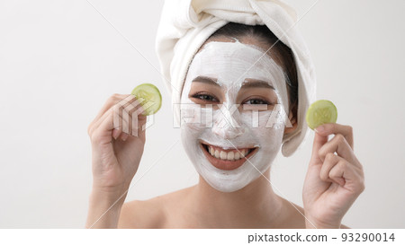 Beauty concept of 4k Resolution. Asian girl putting cucumber at her eyes on a white background. 93290014