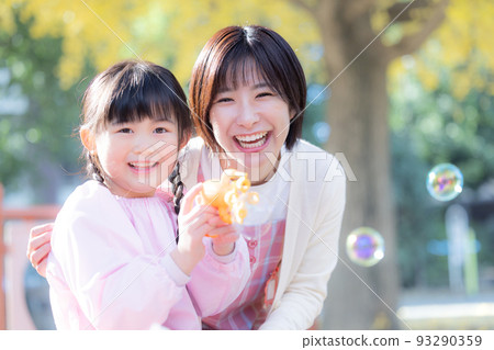 一個女孩和一個幼兒園老師在公園裡玩肥皂泡 93290359