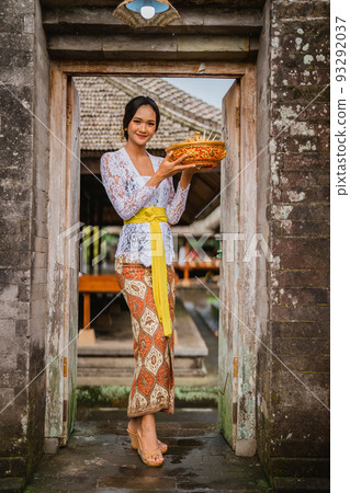 woman with balinese kebaya open her house door in the morning 93292037