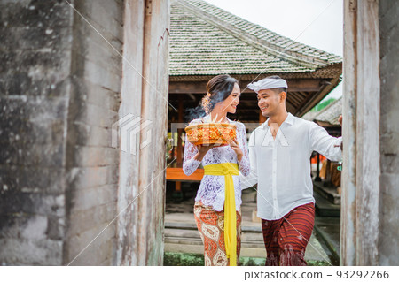 balinese couple going to pura to pray and make offering to the god balinese couple going to pura to pray and make offering to the god 93292266