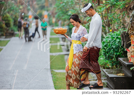 balinese couple going to pura to pray and make offering to the god balinese couple going to pura to pray and make offering to the god 93292267