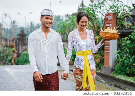 balinese couple walking in pengelipuran village wearing kebaya 93292396