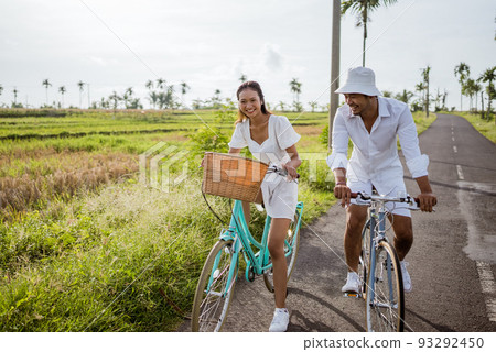 young asian couple riding bicycles along road in summer young asian couple riding bicycles along road in summer 93292450
