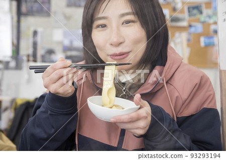A young woman eating a pan in a mountain lodge 93293194
