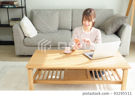 看著電腦和智能手機在客廳裡的女人 93295511