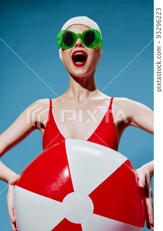 Agitated screaming girl in a red swimsuit with a swimming ball screams and invites you on vacation 93296223