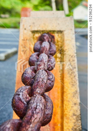 Old rusted chain link connecting dividers by water 93296294
