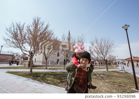 father carrying her daughter on his shoulder while visiting mosque 93298096