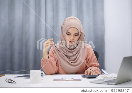 Stressed muslim woman calculating monthly financial, plan budget on computer, pay bills or taxes online at home. Stressed muslim woman calculating monthly financial, plan budget on computer, pay bills or taxes online at home. 93298847