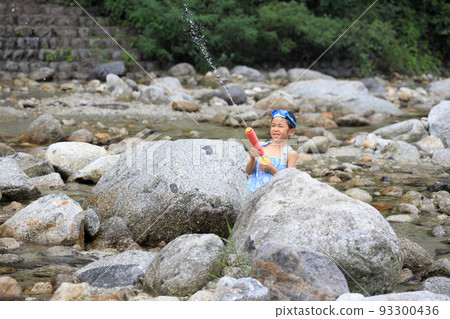 Elementary school girl (7 years old) playing in the river with a water gun Elementary school girl (7 years old) playing in the river with a water gun 93300436