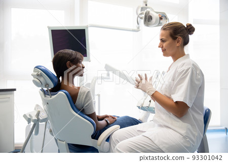 Smiling female patient having consultation at dentist office 93301042