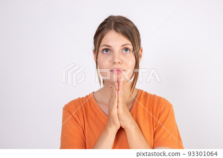 Portrait of young woman wearing orange T-shirt praying 93301064