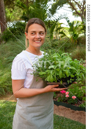 Happy woman holding salad seedlings Happy woman holding salad seedlings 93301072