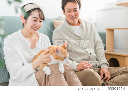 A couple / couple (owner) stroking a pet cat 93301634