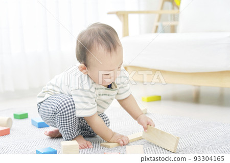 Baby playing with building blocks alone in the living room 93304165