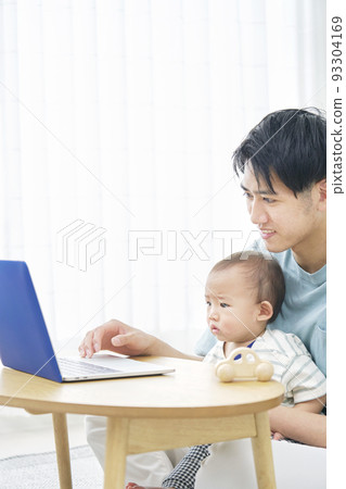 father looking at baby and laptop 93304169