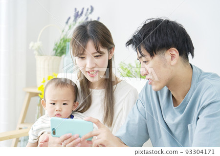 父母和寶寶在客廳看智能手機 93304171
