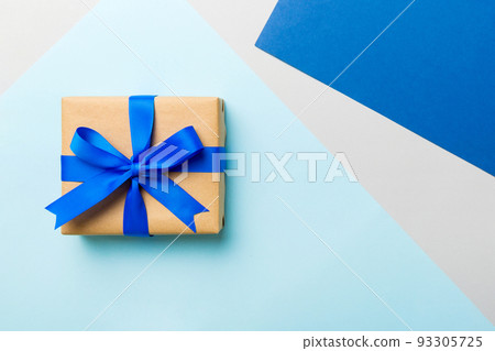 holiday handmade paper present tied blue ribbon bow top view with copy space. Flat lay holiday background. Birthday or christmas present. Christmas gift box concept with copy space holiday handmade paper present tied blue ribbon bow top view with copy space. Flat lay holiday background. Birthday or christmas present. Christmas gift box concept with copy space 93305725